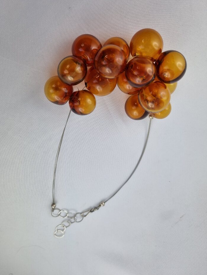 Edelstahlseil mit 15 transparent Topaz farbigen runden Glas Hohlperlen, silberne Verlängerungskette mit Hakenverschluß, liegend