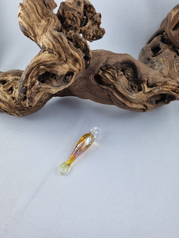Anhänger minimalistischer Fisch aus gelbgold glänzendem Glas mit klarer Kautschukkette liegend