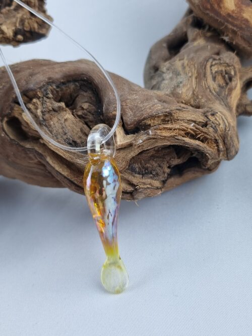 Anhänger minimalistischer Fisch aus gelbgold glänzendem Glas mit klarer Kautschukkette auf Ast
