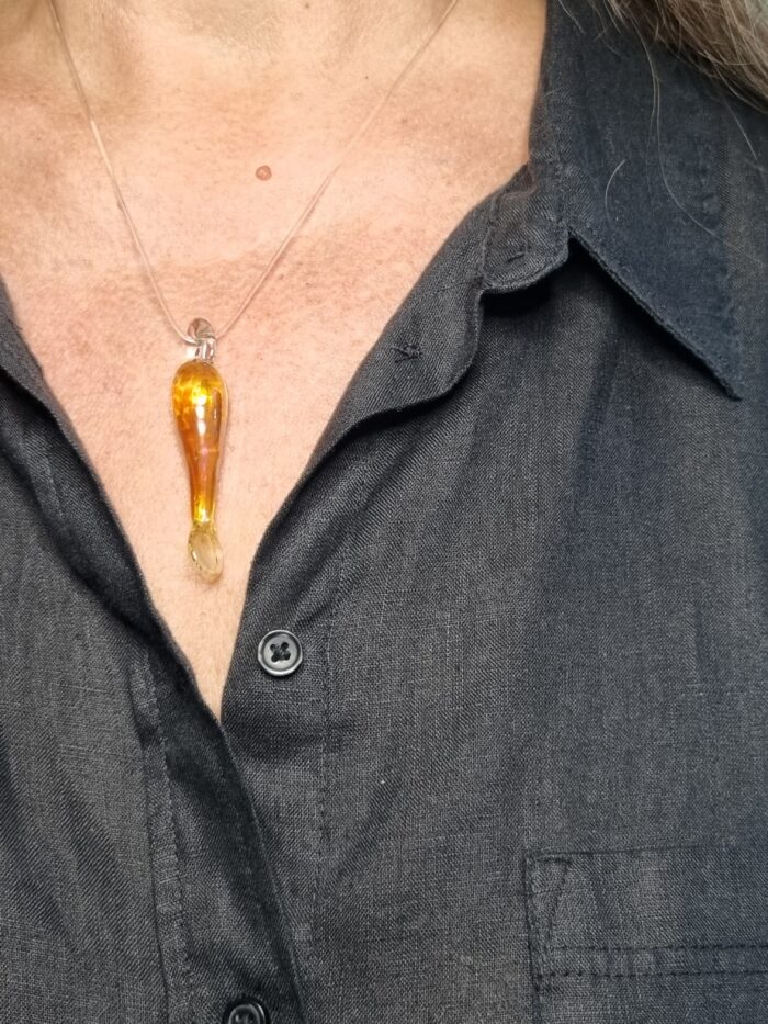 Anhänger minimalistischer Fisch aus gelbgold glänzendem Glas mit klarer Kautschukketan einem Hals , schwarz gekleidet