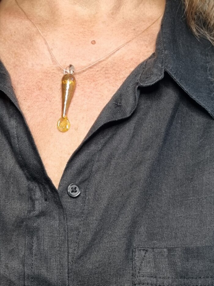 Anhänger minimalistischer Fisch aus gelbgold glänzendem Glas mit klarer Kautschukketan einem Hals , schwarz gekleidet
