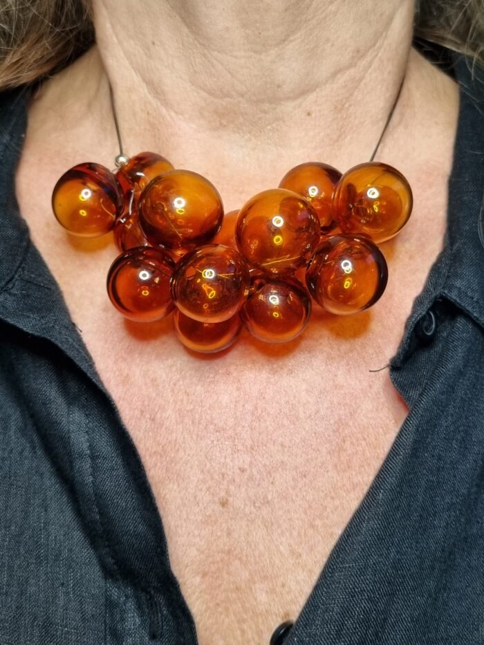 Edelstahlseil mit 15 transparent Topaz färbigen runden Glas Hohlperlen an einem Hals - Tragefoto mit schwarzer Bluse