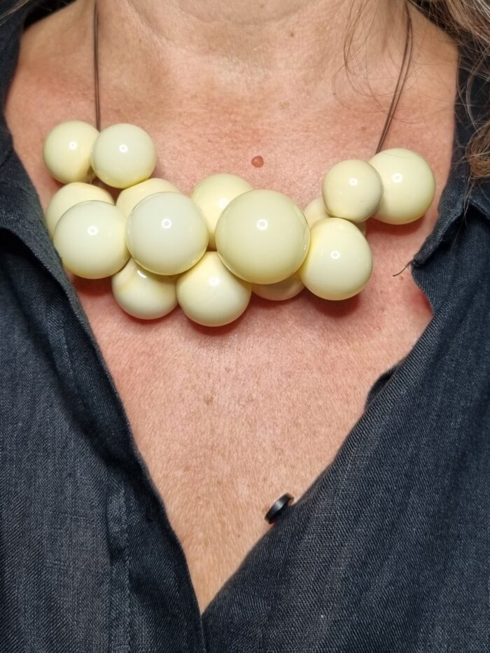 Edelstahlseil mit 15 buttergelben runden Glas Hohlperlen an einem Hals - Tragefoto mit schwarzer Bluse