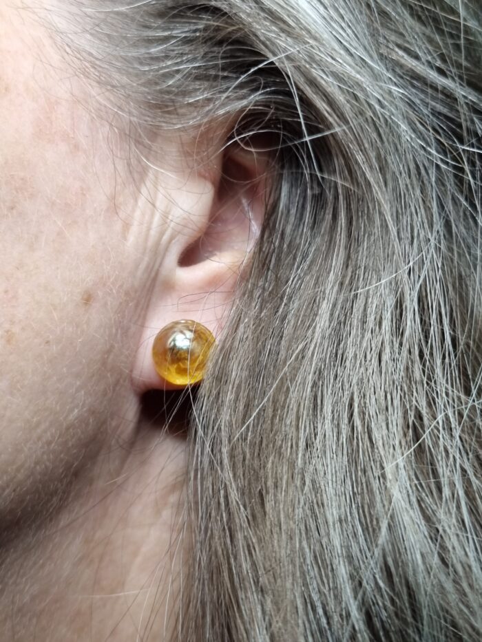 Ohrstecker aus gelbgoldenem glänzendem Glas auf Ohr - Tragefoto