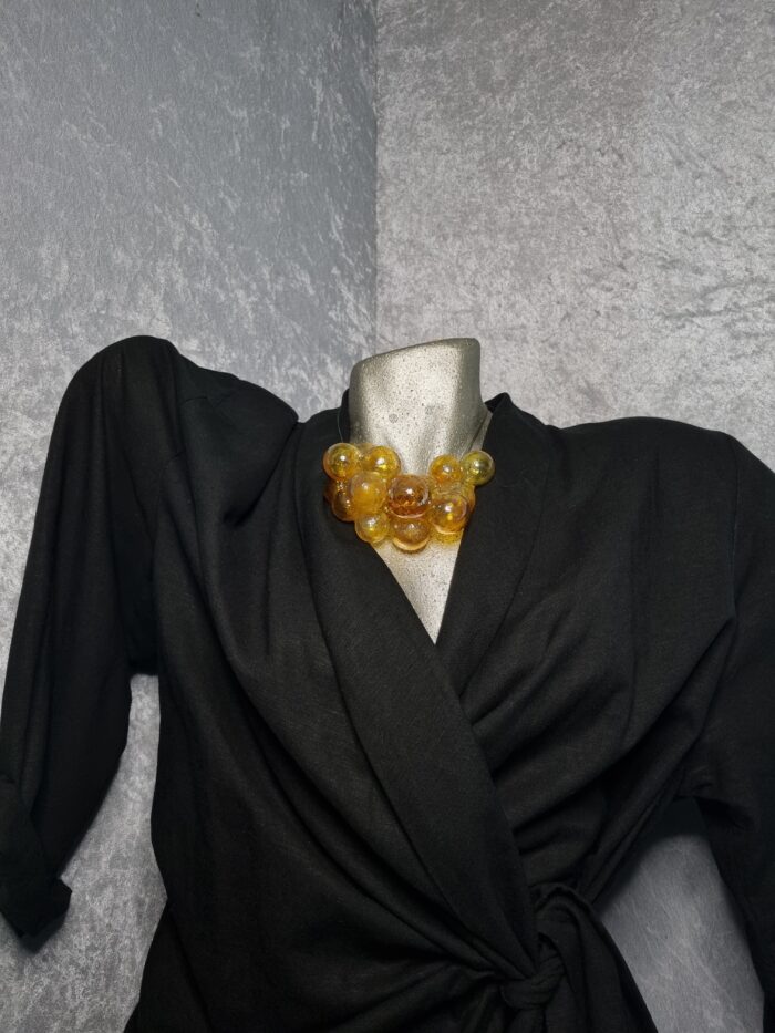 e Edelstahlseil mit 15 transparent gelbgolden glänzenden runden Glas Hohlperlen auf Styroportorso schwarz bekleidet