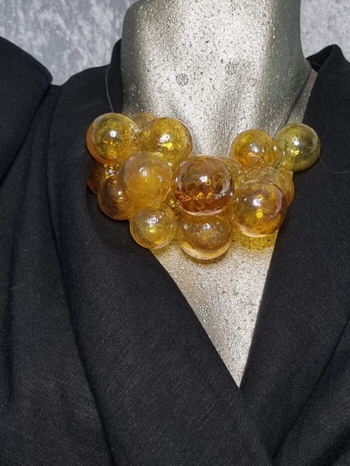e Edelstahlseil mit 15 transparent gelbgolden glänzenden runden Glas Hohlperlen auf Styroportorso schwarz bekleidet