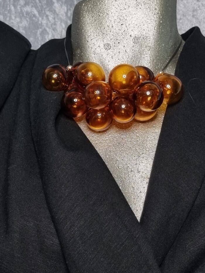 e Edelstahlseil mit 15 transparent Topaz färbigen runden Glas Hohlperlen auf Styroportorso schwarz bekleidet