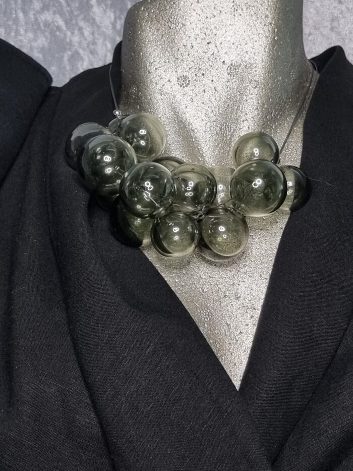 e Edelstahlseil mit 15 transparent mittelgrauen runden Glas Hohlperlen auf Styroportorso schwarz bekleidet